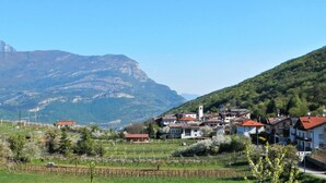 A rural village with houses, vineyards, and a mountain backdrop.