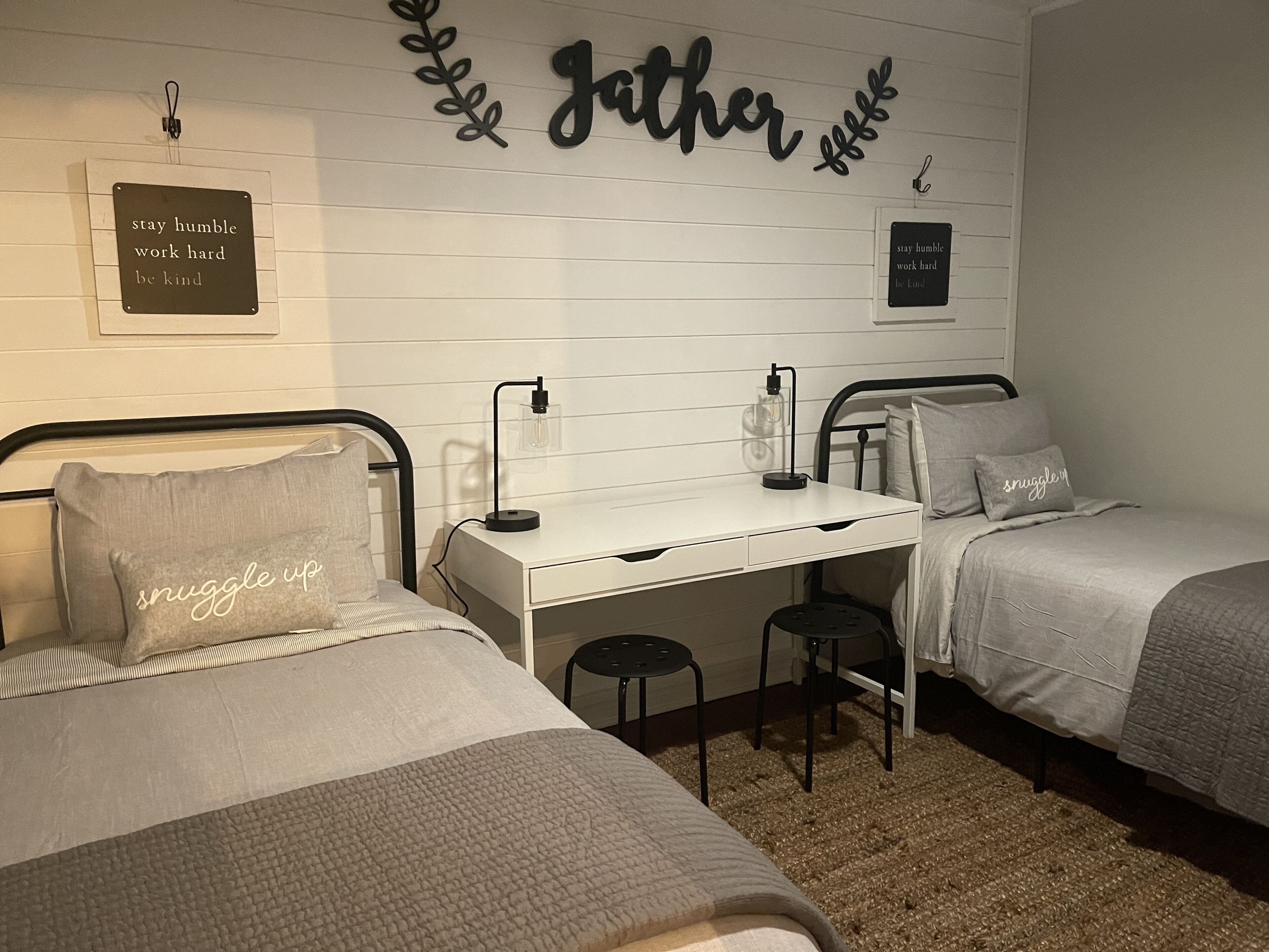 Une chambre avec deux lits, un bureau et des décorations murales inspirantes.