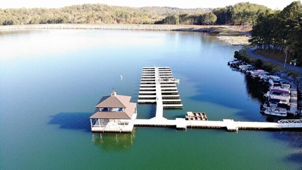 A marina with docked boats, a small building with a roof, and a dock extending into the water.