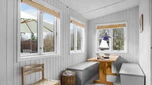 A cozy room with a wooden bench, a small table, and a wicker basket. - Beach front home in Nykøbing Sj with WiFi (Nykøbing Sj)