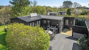 A wooden cabin with a patio, a grill, and a small deck. - Beach front home in Nykøbing Sj with WiFi (Nykøbing Sj)