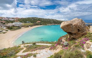 A coastal landscape with a large rock formation, clear turquoise waters, and a sandy beach. - Beach front apartment (Sant.Teresa di Gallura)