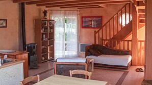 Ein gemütliches Wohnzimmer mit einer Couch, einem Esstisch und einer Treppe, die zu einer weiteren Ebene führt.