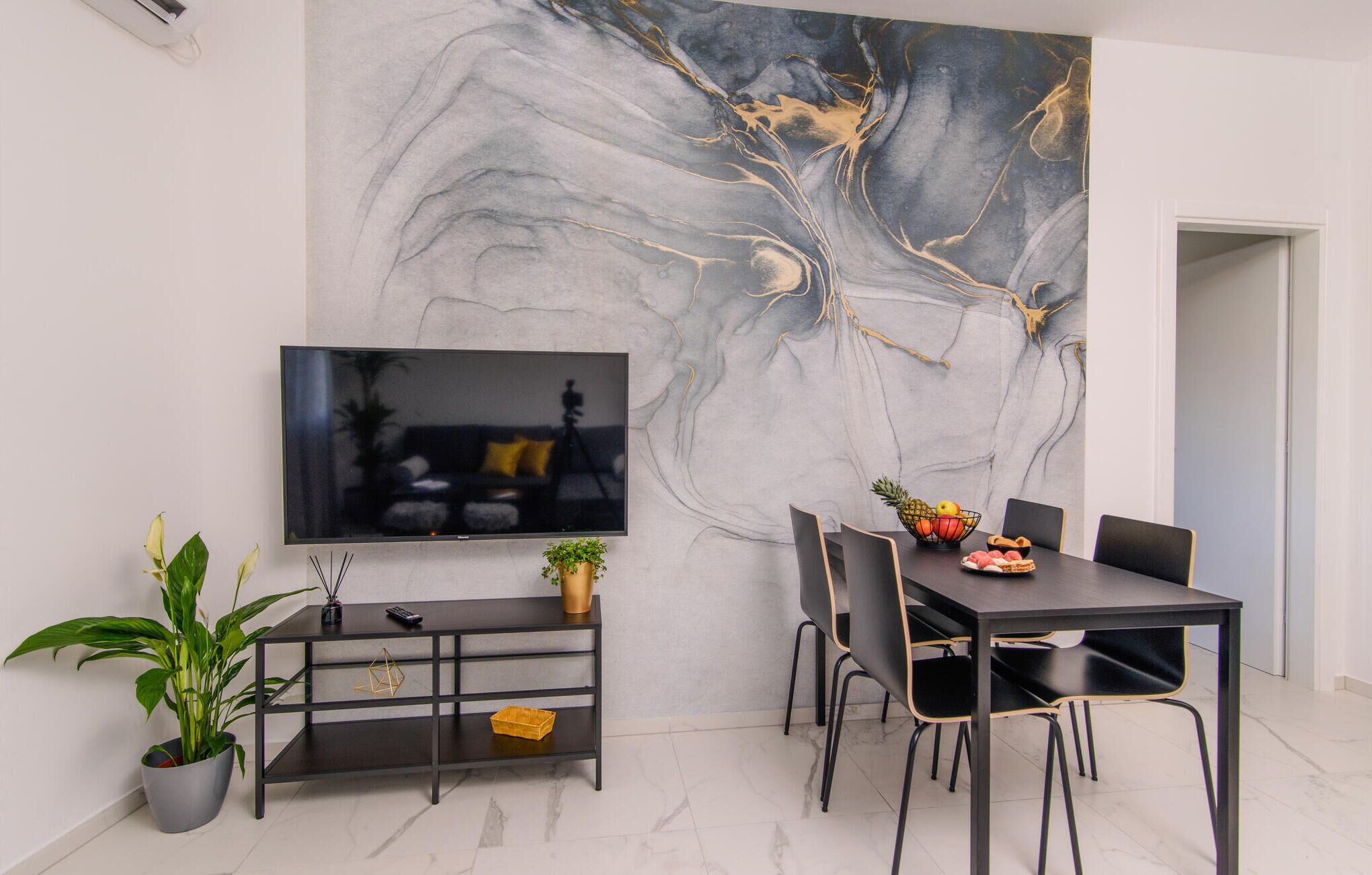 Un comedor moderno con un cuadro abstracto de gran tamaño, un televisor de pantalla plana y una mesa de comedor con sillas.