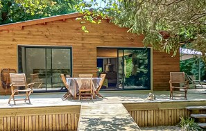 Une cabane en bois dotée d’une terrasse, d’une table à manger et de chaises.