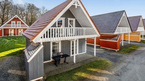 A row of small, single-story cabins with white railings and dark roofs, arranged on a gravel path with a grassy area in the background. - 4 bedroom lovely home in Gråsten (Gråsten)