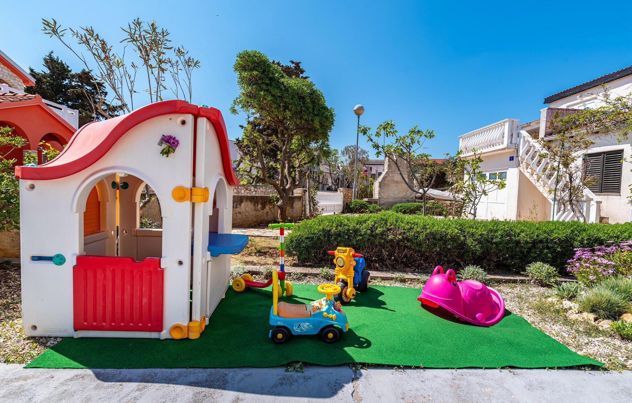 A children's play area with a small house, a slide, and various toys.