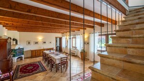 Une salle à manger spacieuse avec un plafond en bois, un escalier et une vue sur l’extérieur.