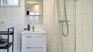 Une salle de bain avec un lavabo blanc, un miroir au-dessus et une douche avec un rideau.