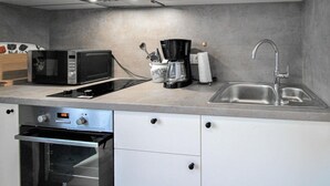 Une cuisine équipée d’un four à micro-ondes, d’une machine à café, d’un évier et d’un four.
