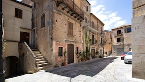 A narrow cobblestone street lined with historic buildings, featuring a staircase leading to an upper level, and a parked car on the right. - Awesome apartment in Caulonia Marina with WiFi (Caulonia Marina)