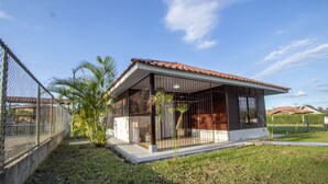 A modern house with a tiled roof, a fenced yard, and a small palm tree. - Cabaña SantaClara your best choice (La Fortuna)