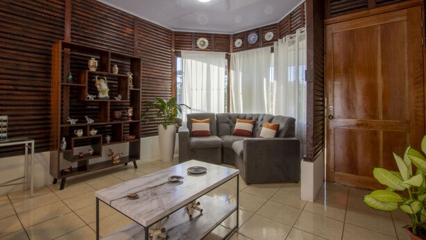A living room with a sofa, coffee table, and wooden shelves with decorative items. - Cabaña SantaClara your best choice (La Fortuna)