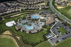 Vue aérienne d’un quartier résidentiel avec une piscine, des courts de tennis et un club-house.