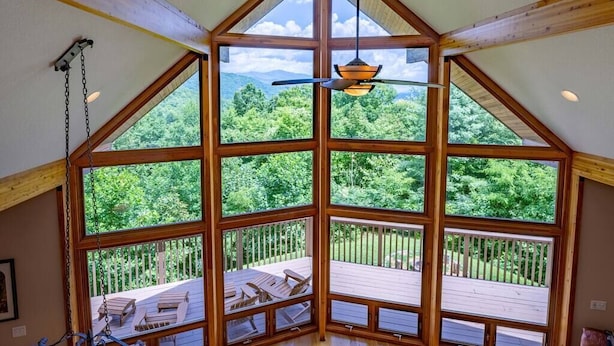 Une pièce dotée de grandes fenêtres donnant sur une terrasse en bois et une végétation luxuriante.