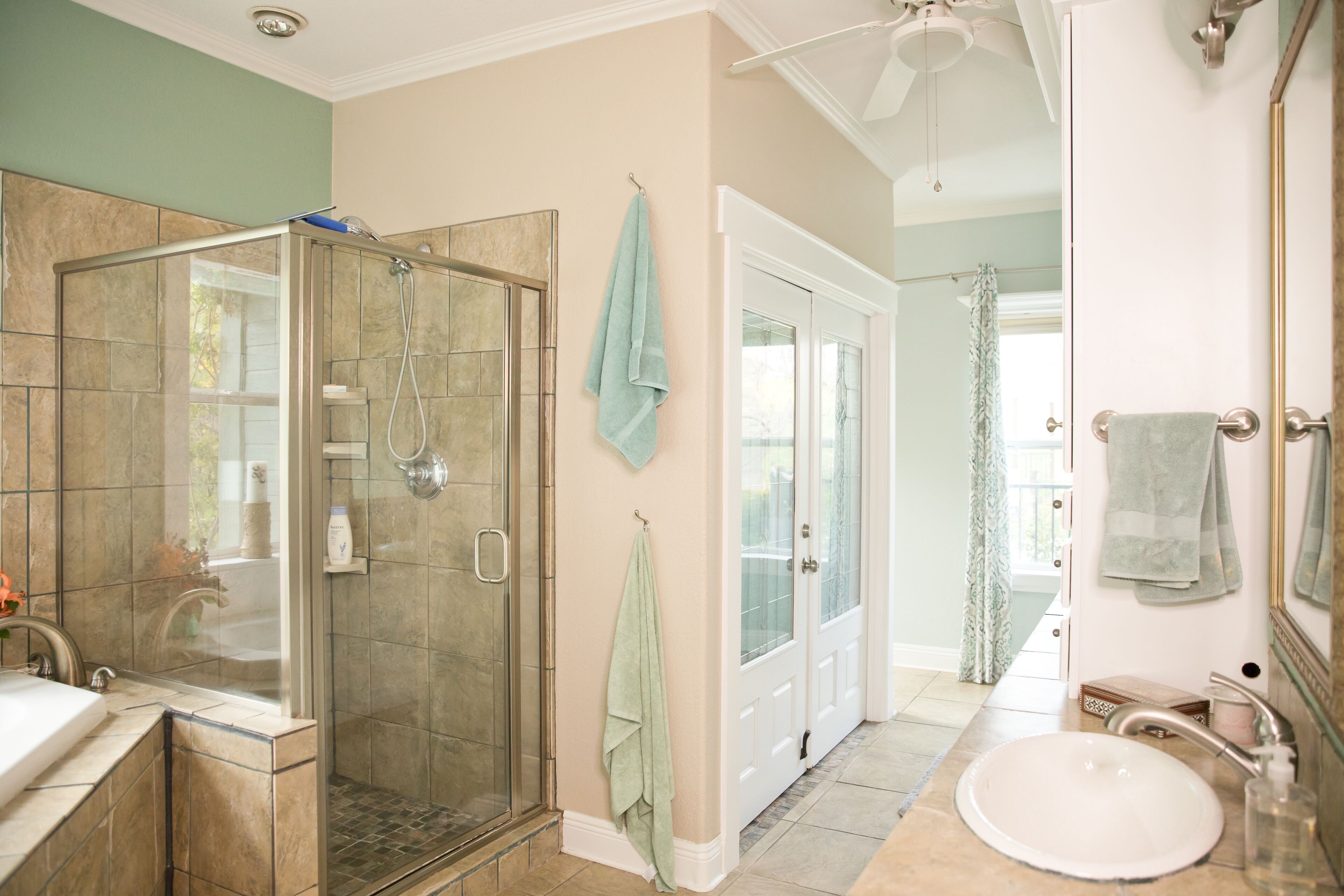 A bathroom with a glass-enclosed shower, a sink, and a mirror.