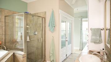 A bathroom with a glass-enclosed shower, a sink, and a mirror.