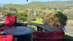 A patio with a round table and red chairs, overlooking a scenic valley with hills and a river. - Beautiful Villa with Pool & Scenic Views in foothills close to Sequoia's (Exeter)