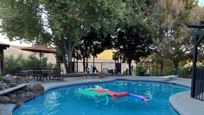 A swimming pool with a built-in slide, surrounded by a deck area with outdoor furniture and a pergola. - Beautiful Villa with Pool & Scenic Views in foothills close to Sequoia's (Exeter)
