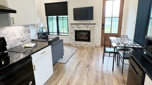 Una cocina moderna con chimenea, suelo de madera y un comedor con mesa y sillas.