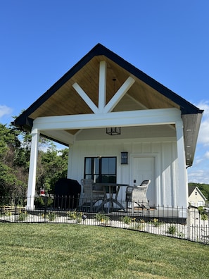 A covered patio area with a white exterior, a wooden ceiling, and a black roof.