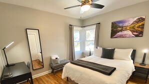A bedroom with a bed, bedside tables, a desk, a mirror, a ceiling fan, and a window with curtains. - Lavish Luxury in a Lush Locale (Cheyenne)