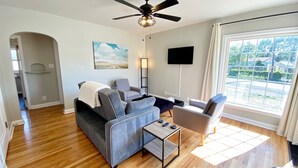 A modern living room with a grey sofa, a coffee table, and a TV mounted on the wall. - Lavish Luxury in a Lush Locale (Cheyenne)