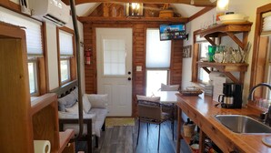 A cozy cabin interior with a wooden interior, a television mounted on the wall, a kitchen area with a sink and coffee maker, and a seating area with a sofa and chairs. - Hoot Owl Cabins -Incredible Lakefront Cabin PLUS a 2nd Tiny Home (Garfield)