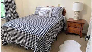 A bedroom with a checkered bedspread, a nightstand with a lamp, and a white furry rug.