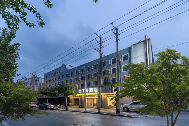 A multi-story hotel with a modern facade, a visible restaurant or cafe on the ground floor, and a parking area in front.