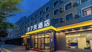A hotel with a modern facade, a prominent entrance with glass doors, and a visible sign indicating it is a 7-day hotel.