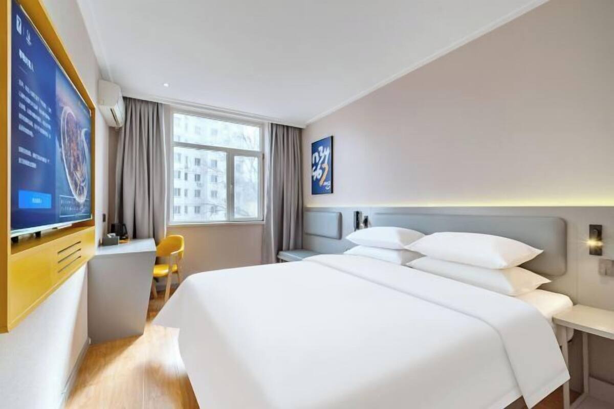 A hotel room with a large bed, a desk, a chair, and a television.