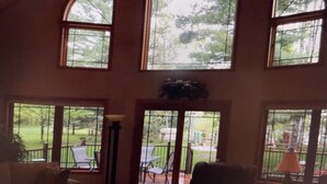A room with large arched windows, a view of a garden, and a patio area with outdoor furniture. - Lake cabin on Holcombe flowage. Loft views, fire pit, and nearby hiking. (Holcombe)