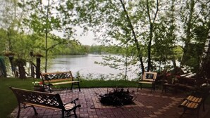 An outdoor seating area with benches and a fire pit, overlooking a body of water. - Lake cabin on Holcombe flowage. Loft views, fire pit, and nearby hiking. (Holcombe)