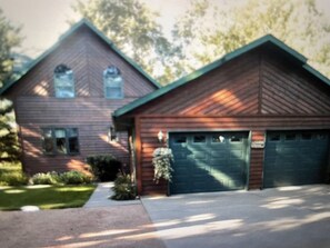 Une maison à deux étages avec un garage, une pelouse devant et une allée.