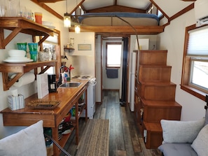 A compact kitchen with wooden shelves, a sink, and a stove.