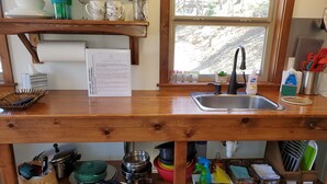 Una cocina con encimera de madera, un fregadero y diversos utensilios y electrodomésticos.