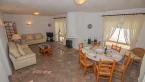 A living room with a sofa, TV, and dining table with chairs. - Casa dos Sonhos Praia da Luz (Luz)