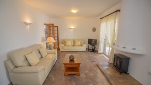 A living room with a beige sofa, a wooden coffee table, a television, and a fireplace. - Casa dos Sonhos Praia da Luz (Luz)
