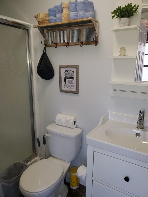 A bathroom with a toilet, sink, and a shelf with towels.