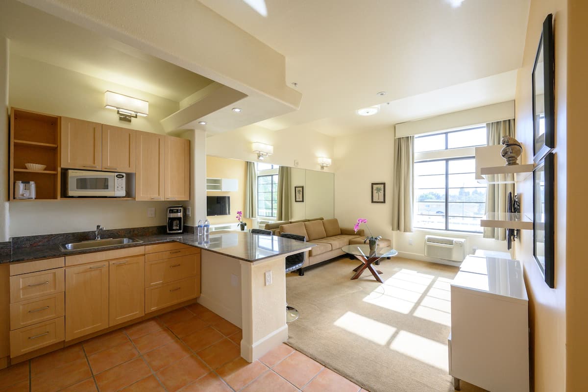 A modern kitchen with a central island, built-in microwave, and a large window providing natural light.