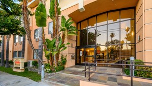 A hotel entrance with a glass facade, palm trees, and a sign for 'Studios Inn'. - Studios Inn (San Jose)