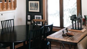 A dining area with a wooden table and chairs, framed pictures on the wall, and a hanging light fixture. - Cute kid-friendly condo next to Dollar Mountain (Sun Valley)
