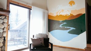 A room with a large window, a stone wall, a mural of mountains, and a wooden bench. - Cute kid-friendly condo next to Dollar Mountain (Sun Valley)