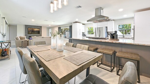 A modern kitchen with a central island, stainless steel appliances, and a dining area with a wooden table and chairs.