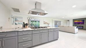 A modern kitchen with grey cabinets, a large island, and a built-in stove.