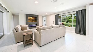 A modern living room with a fireplace, two sofas, a coffee table, and a TV.