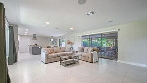 A spacious living room with a large sofa, a coffee table, and a sliding glass door leading to an outdoor area.