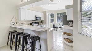 Eine moderne Küche mit weißen Schränken, einem eingebauten Ofen und einer zentralen Kochinsel mit Barhocker.