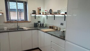 Una cocina moderna con gabinetes blancos, una encimera, un fregadero, un tostador, una tetera y una estufa.